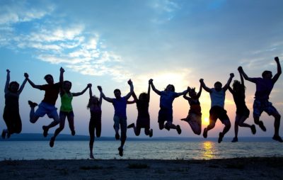 A group of friends holding hands and jumping up in the air