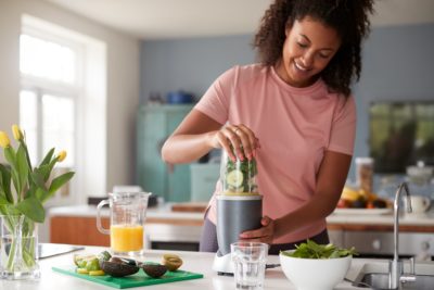 Woman Making Healthy Juice Drink With Fresh Ingredients In Electric Juicer After Exercise
