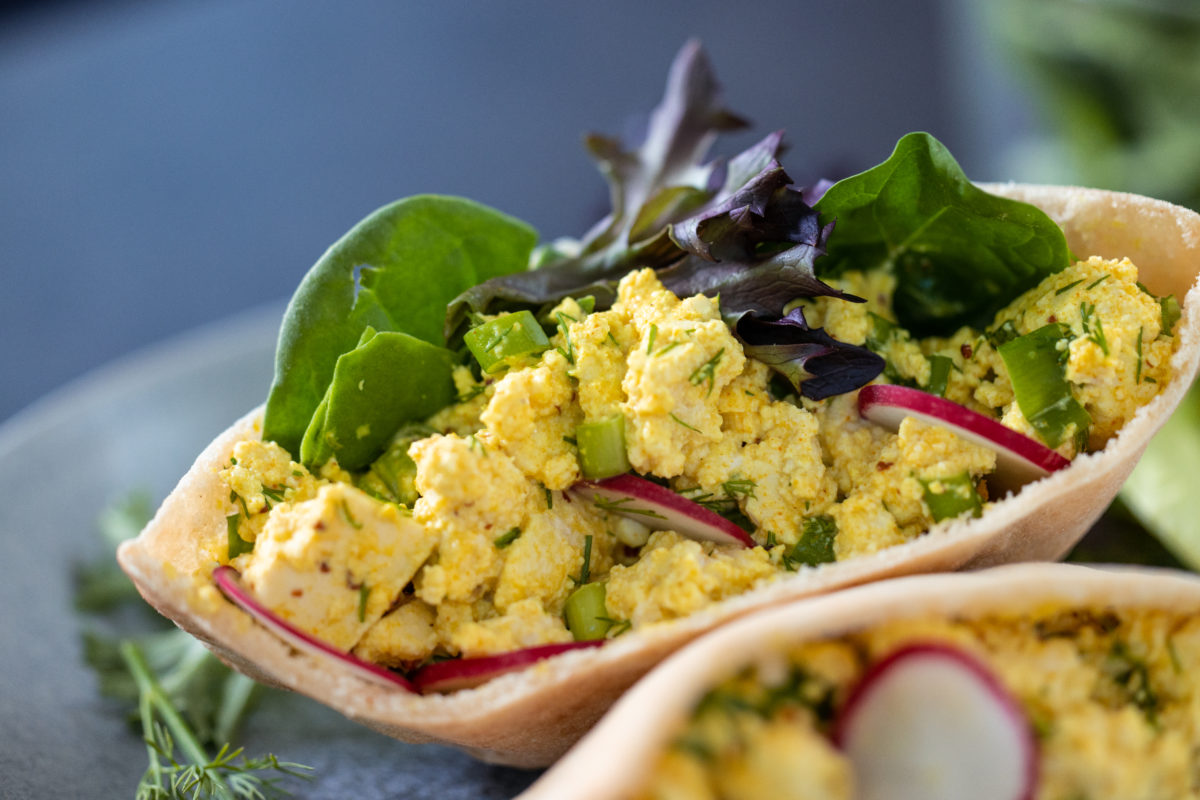a closeup of Wicked's eggless egg salad pita with spinach and radish slices
