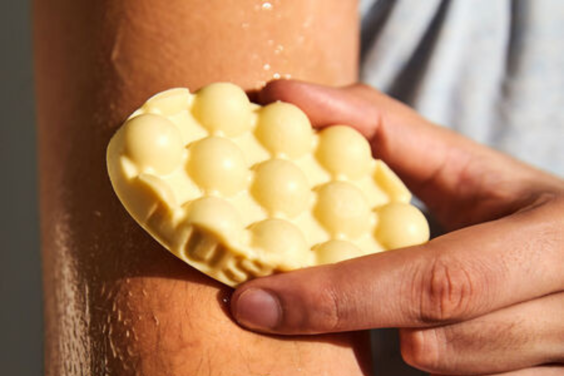 A person rubbing a Lush massage bar on their arm
