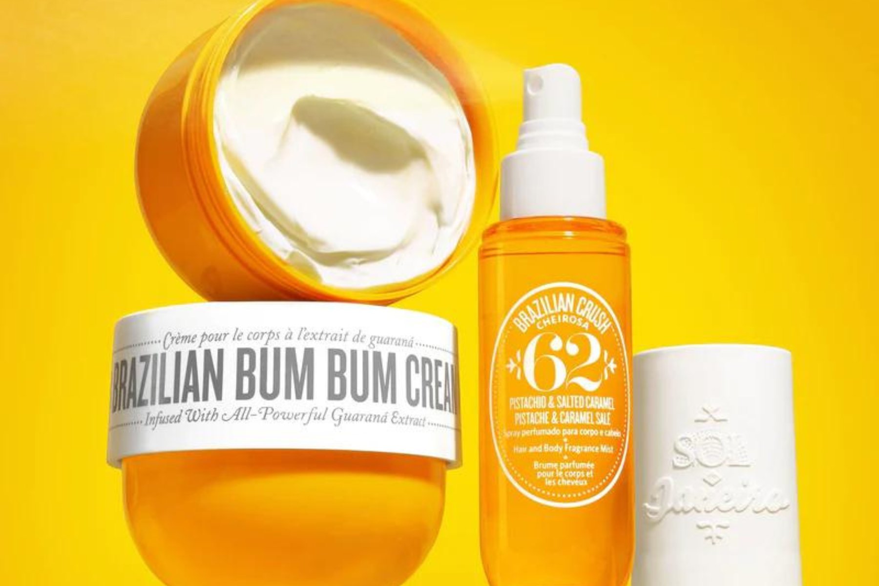 Vegan Valentines gift idea: a tub of Sol de Janeiro cream sits atop a closed one, next to a yellow spritzer bottle of the same yummy scent