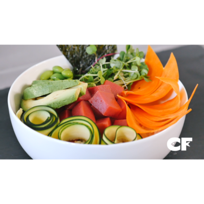 a crisp glossy white bowl filled with fresh carrots, seaweed, avocado, cucumber, and plant-based tuna pieces