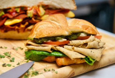 a croissant is stuffed with crisp green lettuce, tomato slices, and Unreal Turk'y