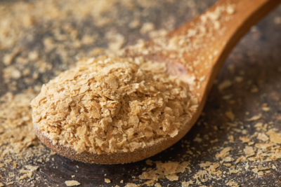Nutritional yeast flakes on a wooden spoon