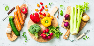 Fresh colorful organic vegetables on wooden chopping (cutting) boards captured from above (top view, flat lay). Grey stone worktop as background. Kitchen - preparing food.