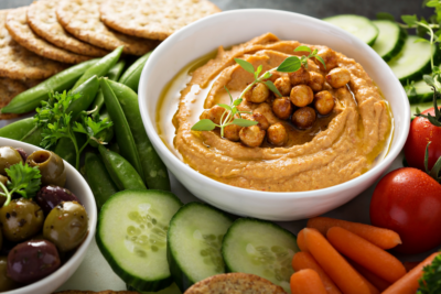 A spread of hummus, assorted vegetables and crackers
